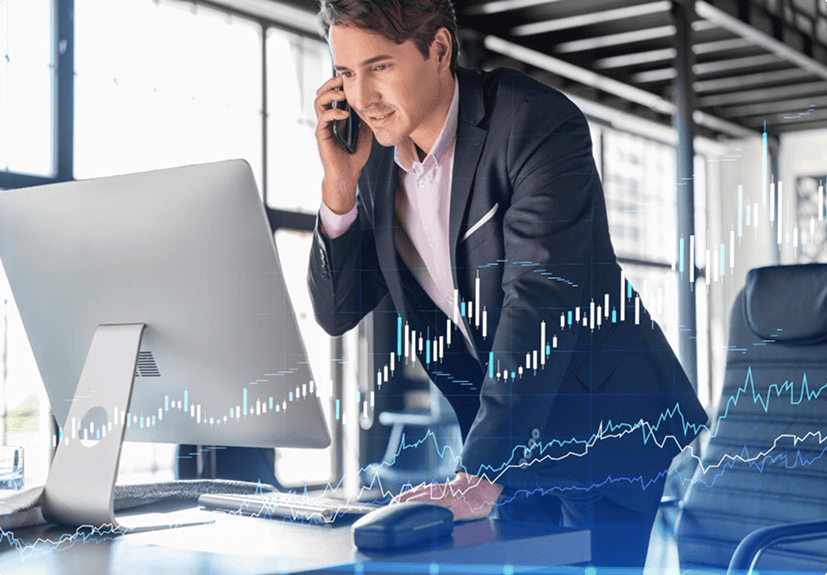 A man in business attire talks on the phone while standing at a desk with a computer; financial graphs and references to Live Sessions are overlaid on the image.